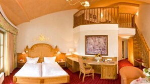 Habitación de hotel con una cama grande, un escritorio, una silla y una escalera que lleva a un nivel superior.