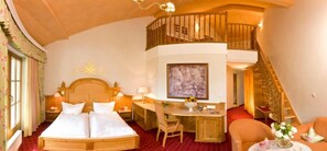 Une chambre d’hôtel avec un grand lit, un bureau, une chaise et un escalier menant à un étage supérieur.