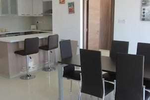 A modern kitchen with white cabinets, a central island with bar stools, and a dining area with black chairs.