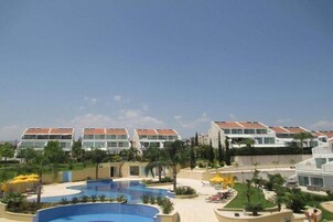 A resort with multiple buildings, a large swimming pool, and outdoor seating areas.
