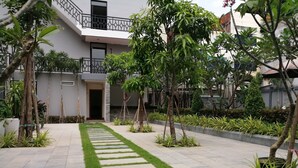 A modern building with a paved courtyard, stone steps, and various plants. - Holiday Hotel (Battambang)