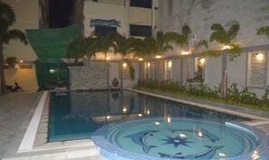 A swimming pool with a dolphin design, surrounded by palm trees and a stone wall. - Holiday Hotel (Battambang)