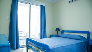 A hotel room with a bed, a desk, a chair, and a view of the outside. - Paphinia Seaview Apartments (Paphos)