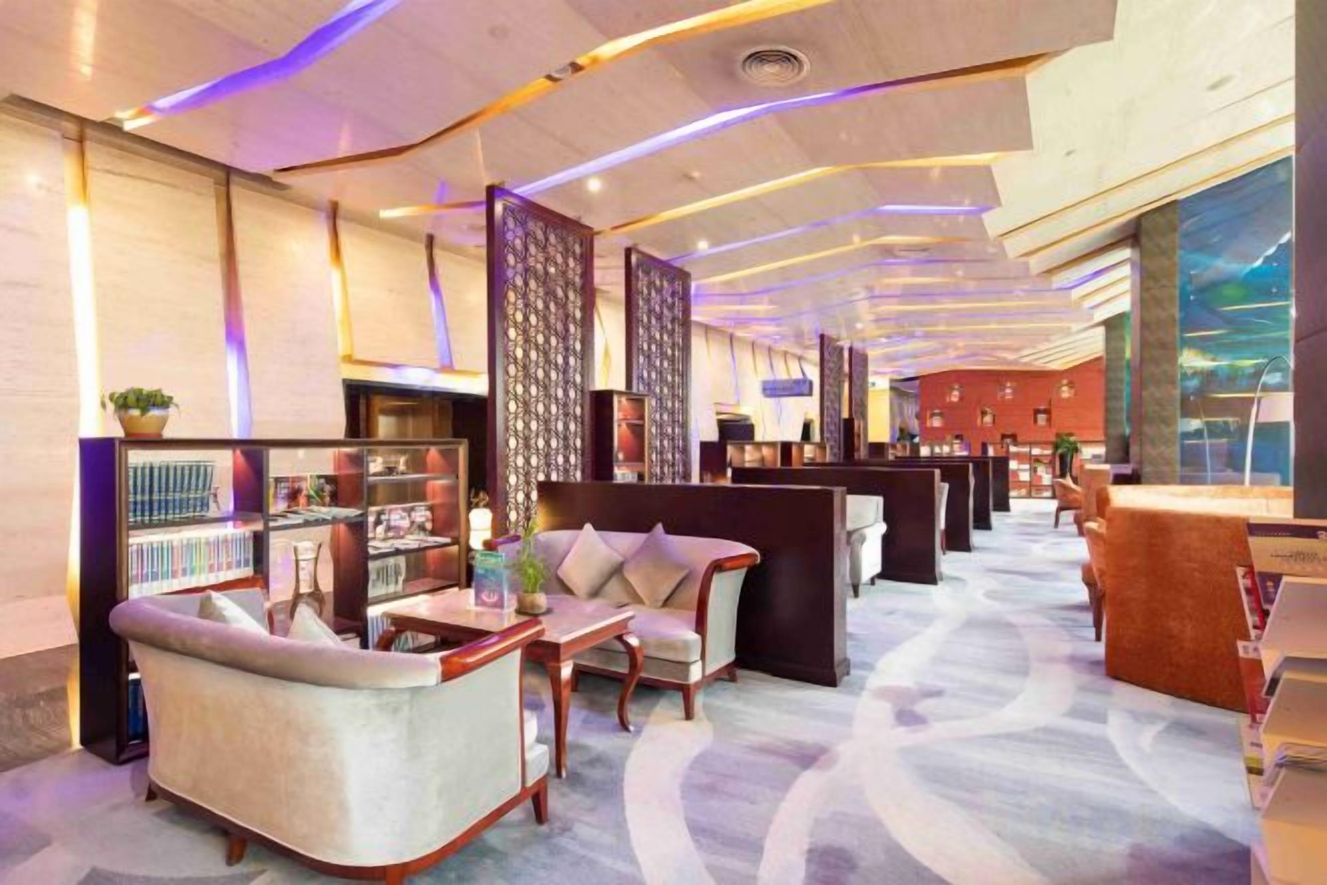 Un vestíbulo de hotel con zonas de estar, una recepción y un amplio ventanal.