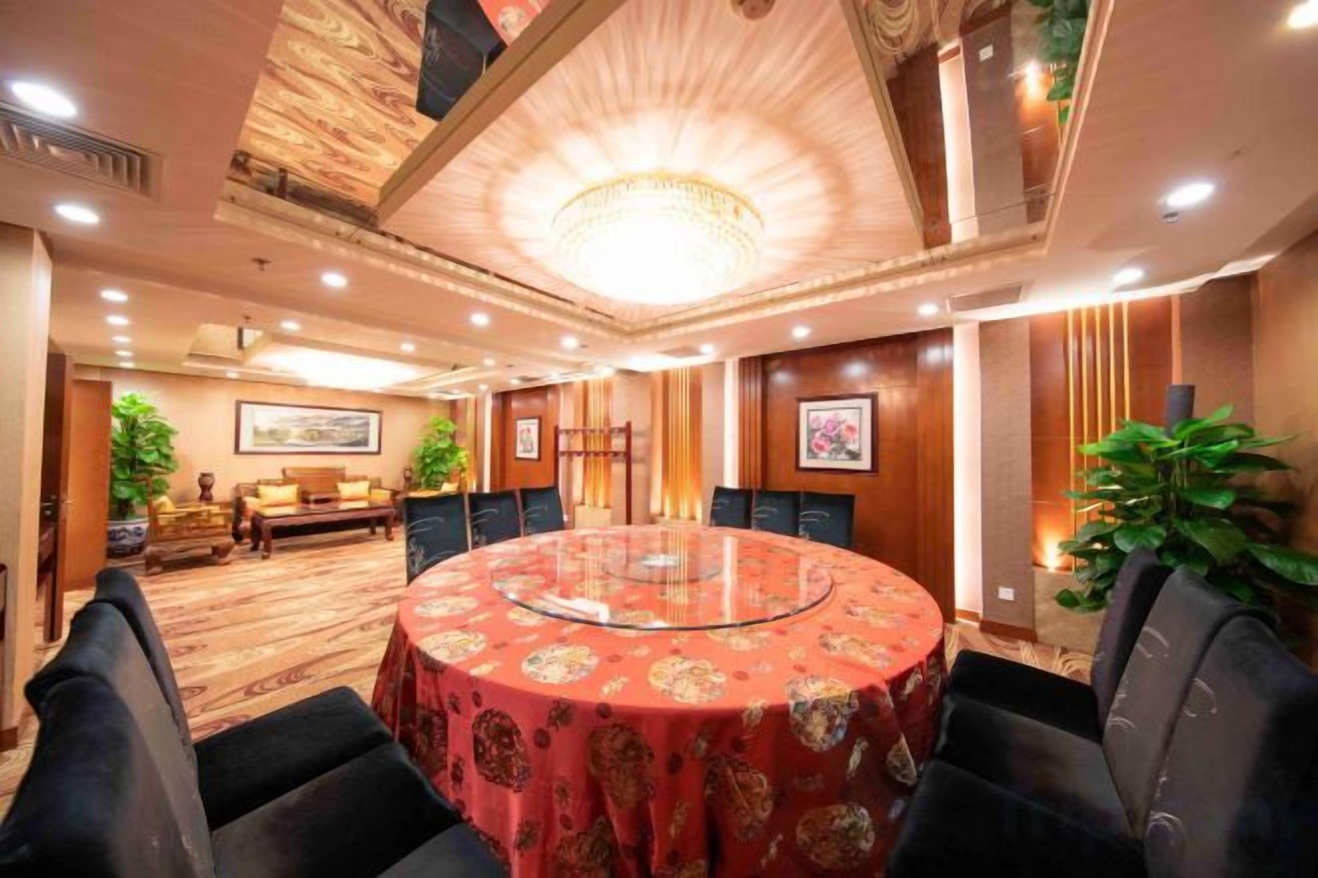 Een vergaderzaal met een ronde tafel, stoelen en een kroonluchter.