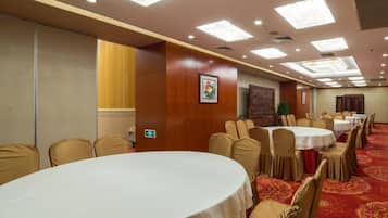 A conference room with round tables, chairs, and a carpeted floor.