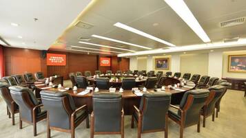 A conference room with a large oval table surrounded by chairs, equipped with nameplates and water bottles.