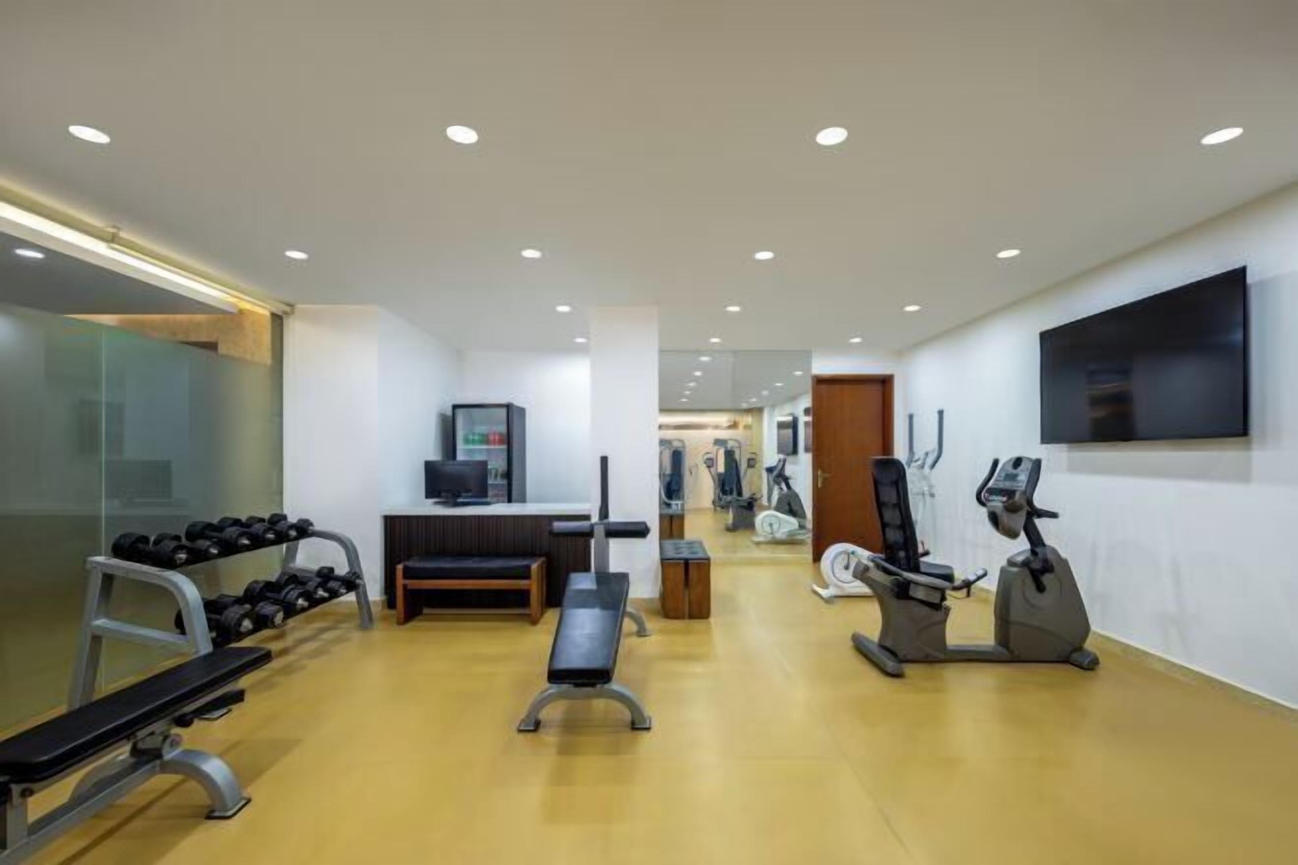 Une salle de sport moderne équipée de machines de cardio, de poids libres et d’un banc de musculation.