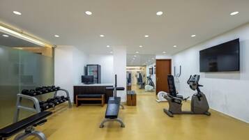 Une salle de sport moderne équipée de machines de cardio, de poids libres et d’un banc de musculation.