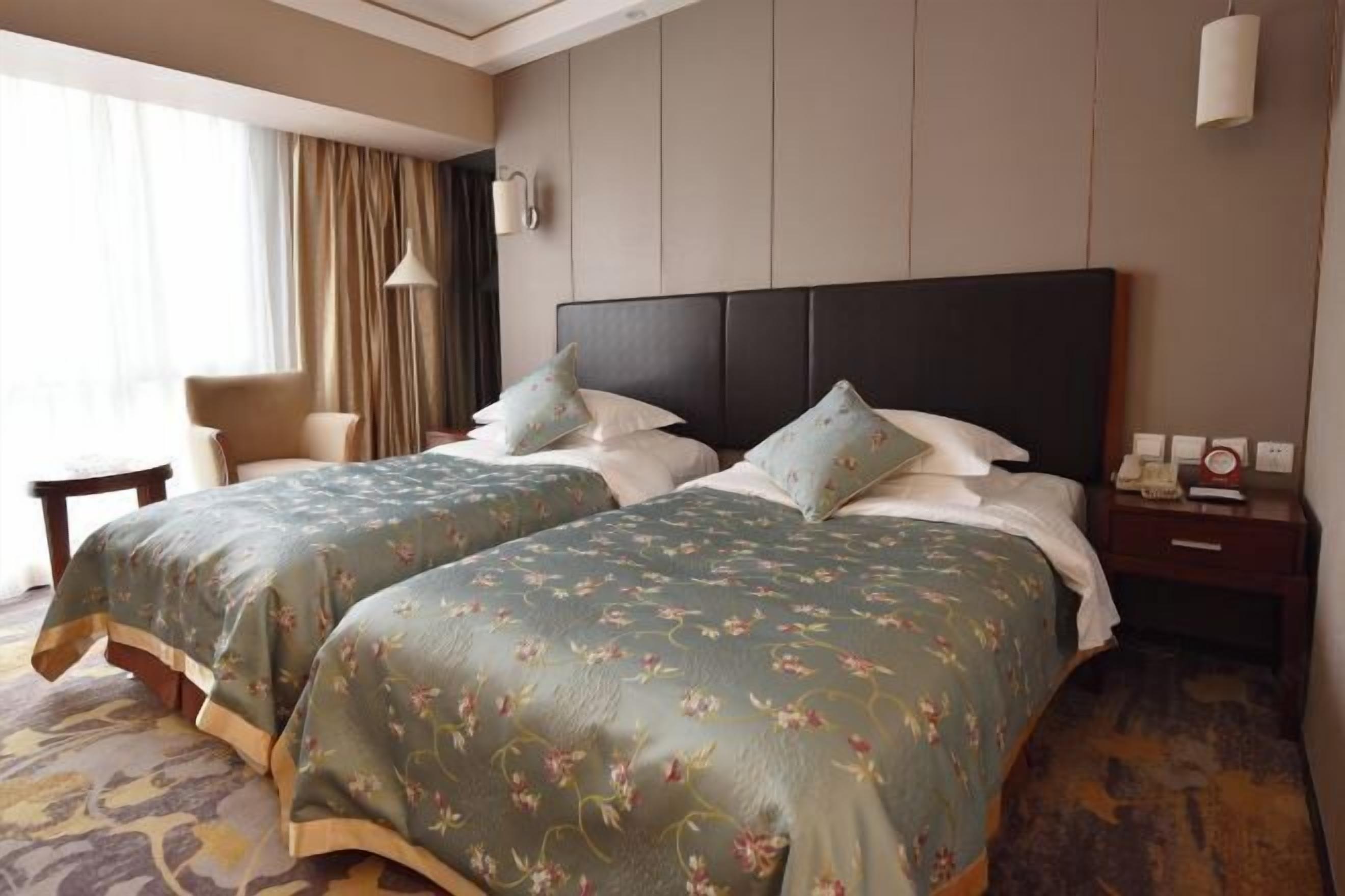 Une chambre d’hôtel avec deux lits, une chaise, une table de chevet et une lampe.
