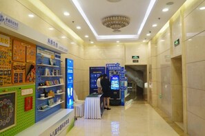 A corridor with a reception desk, a vending machine, and a display of items on shelves. - China Hall of Science and Technology (Beijing)