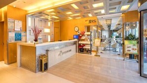 A hotel reception area with a modern design, featuring a reception desk, a clock, and a seating area with tables and chairs. - Jinjiang Inn (Huaibei Mengshan Road) (Huaibei)