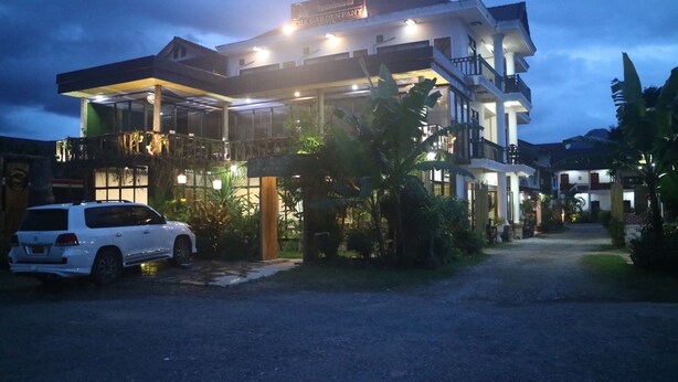 A two-story hotel with a covered entrance and a white car parked in front.