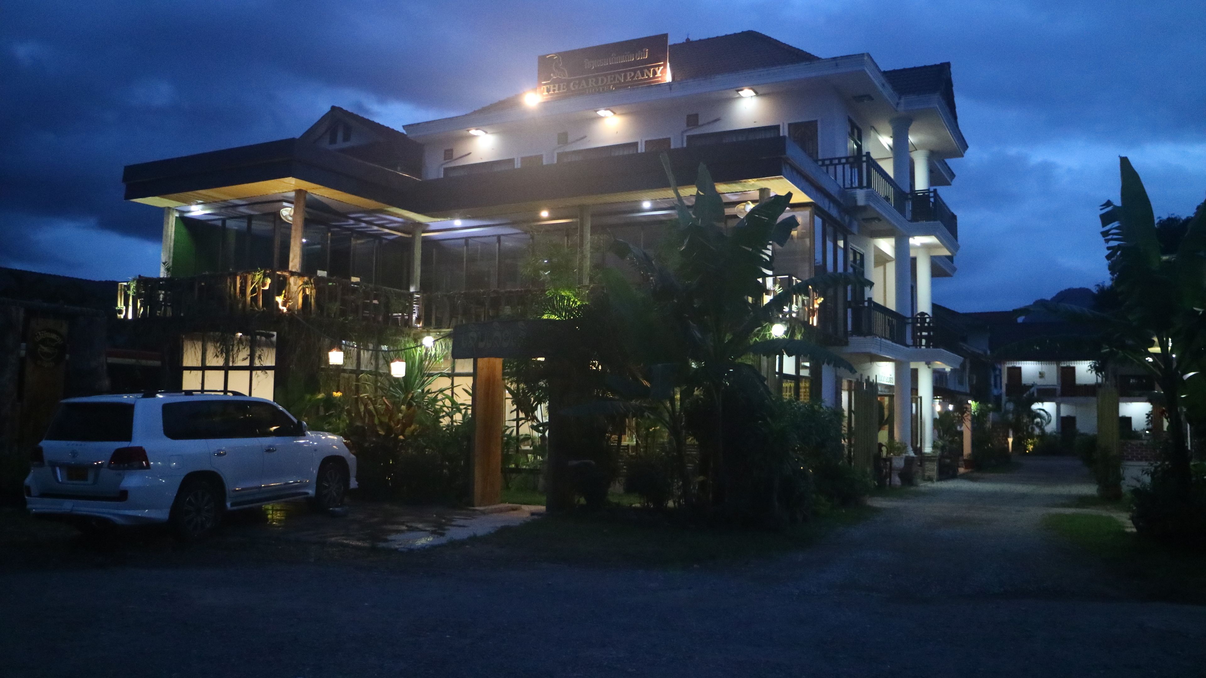 A multi-story hotel with a well-lit entrance and a car parked in front.