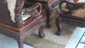 A dining area with ornate wooden furniture, including a table and chairs with intricate carvings.