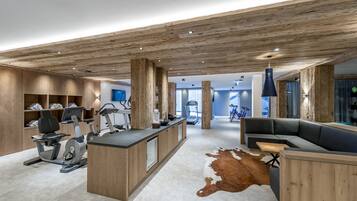 A modern interior with a wooden ceiling, a central island with exercise equipment, a seating area, and a glass wall.