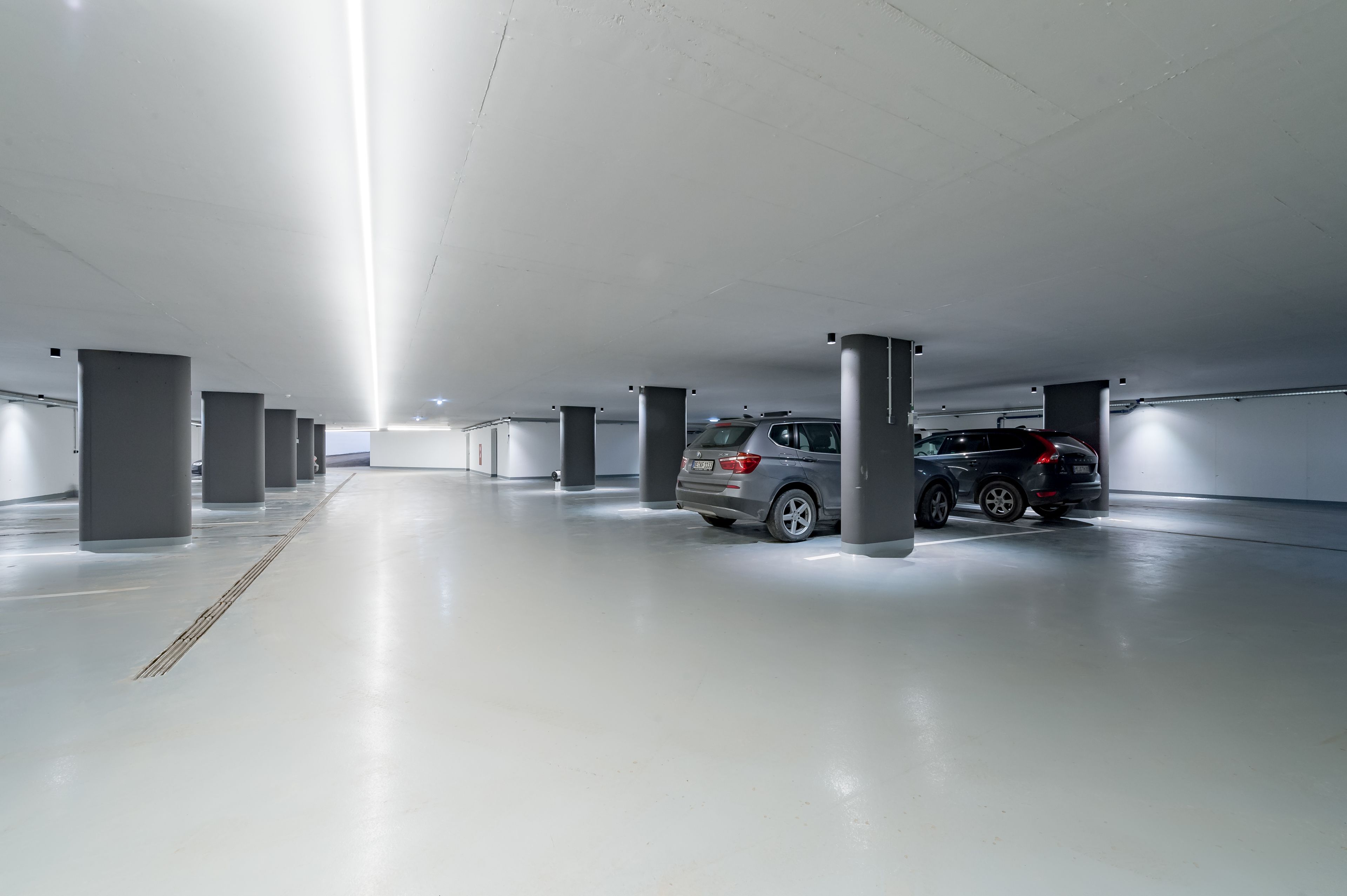 A modern, well-lit parking garage with a clean, polished floor and evenly spaced columns.