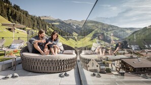 A couple sitting on a circular outdoor sofa with a city view.