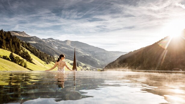 A person in a pool with a mountain backdrop.