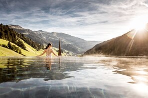Une personne dans une piscine, avec une montagne en arrière-plan.