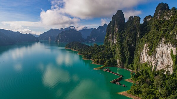A coastal landscape with a clear turquoise sea, steep cliffs, and dense greenery.