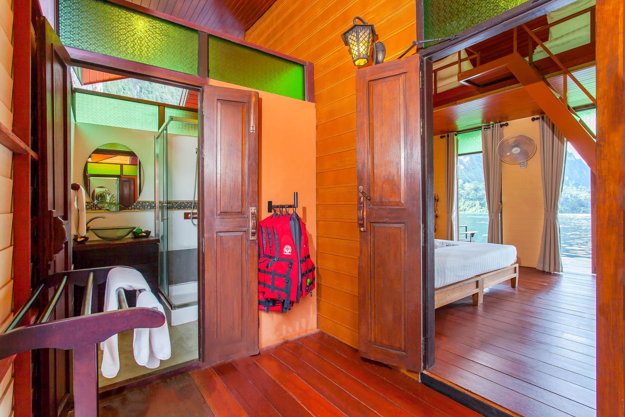 A wooden cabin with a bathroom, a bed, and a view of the water.