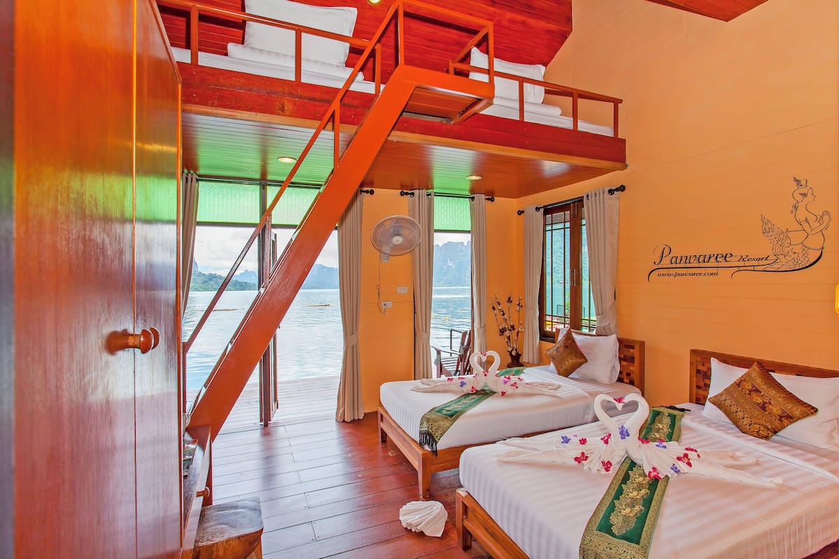A hotel room with two beds, a wooden staircase, and a view of the water.