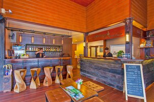 Un rincón acogedor con bar, mobiliario de madera, una barra y un menú en pizarra que ofrece diversas bebidas.