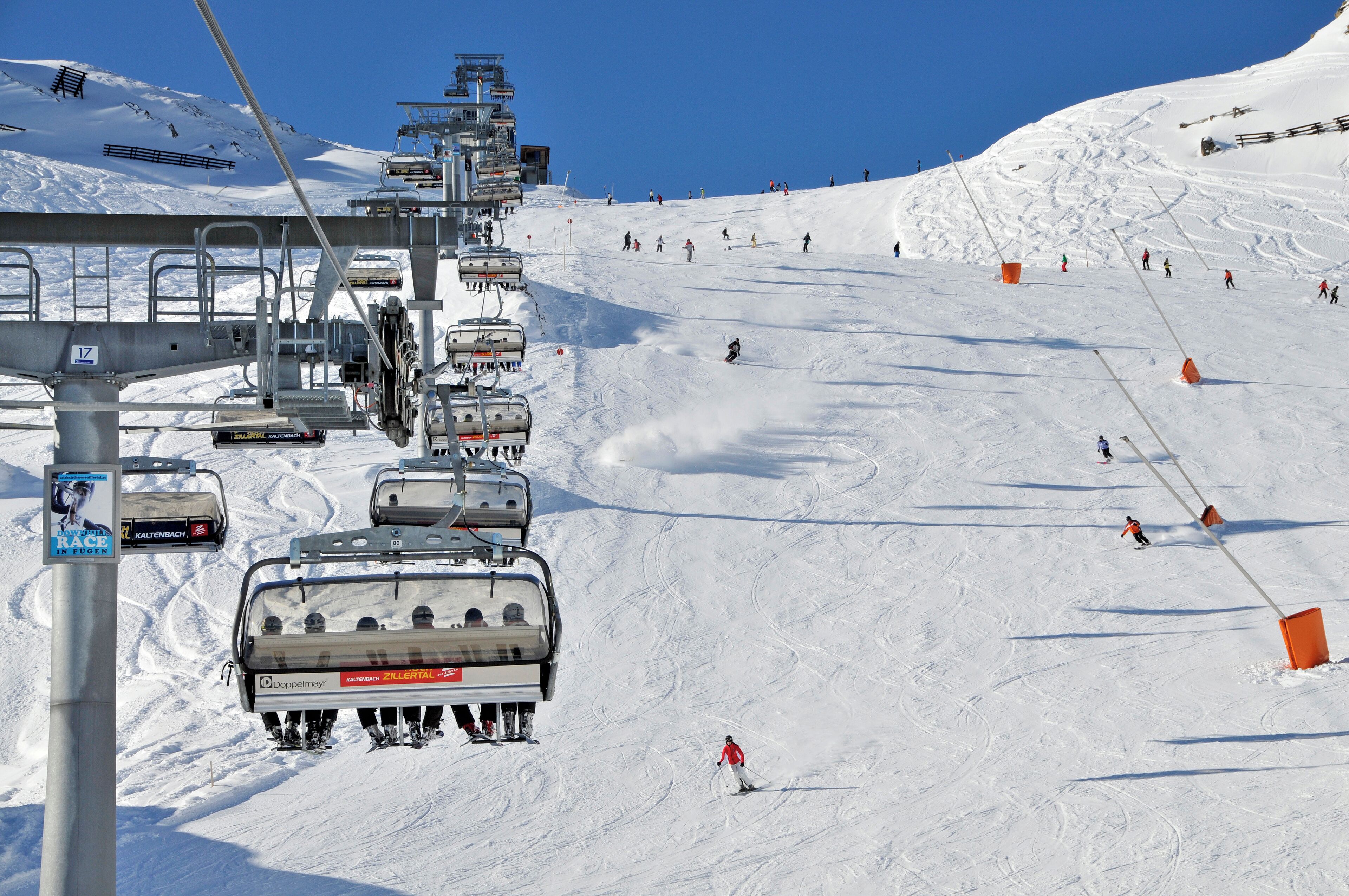 A ski lift with skiers descending a snowy slope.