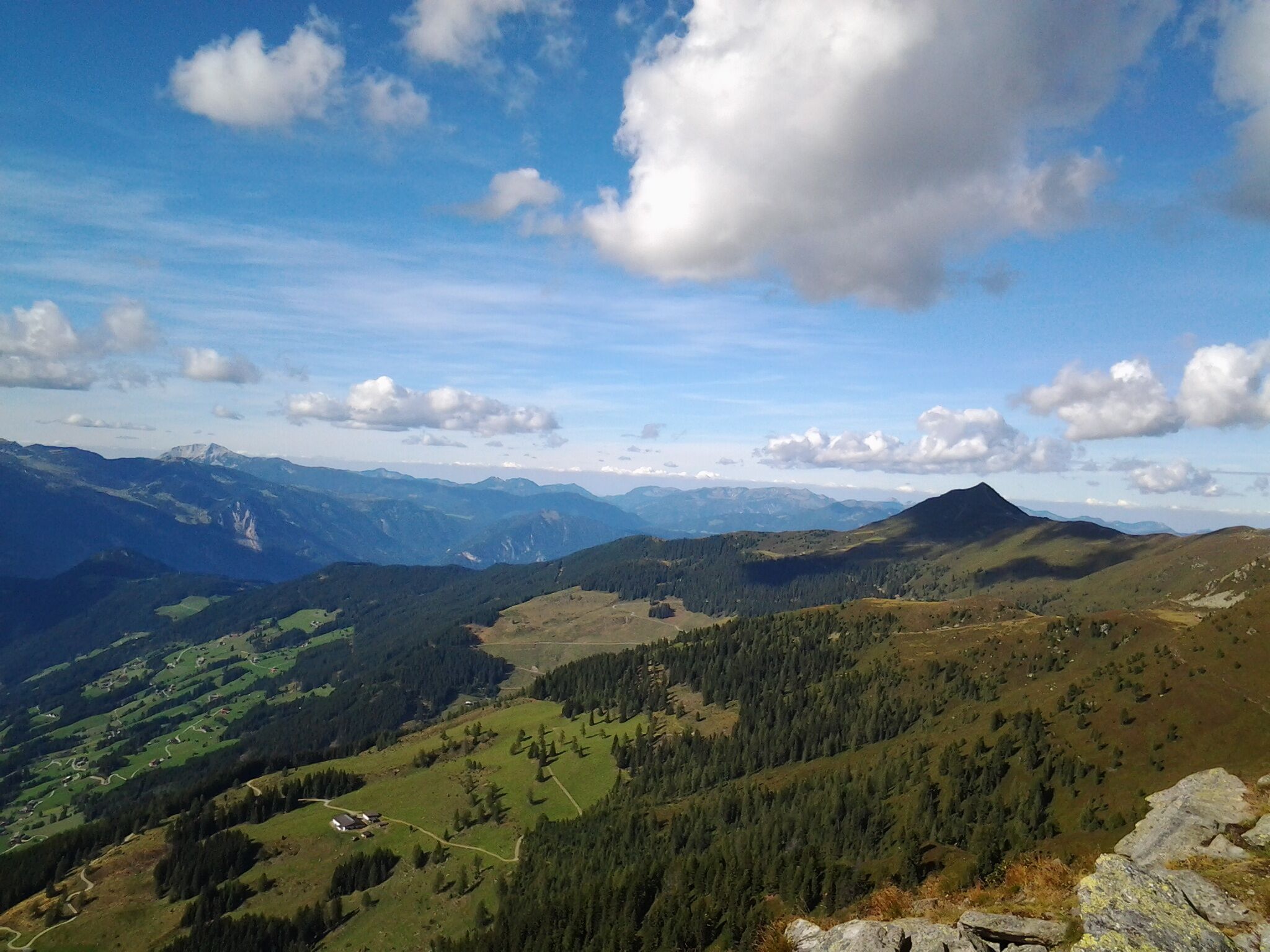 Vista panorámica de un paisaje montañoso con cielo despejado y nubes dispersas.
