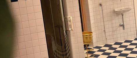 A bathroom with a checkered floor, a shower area, and a sink.