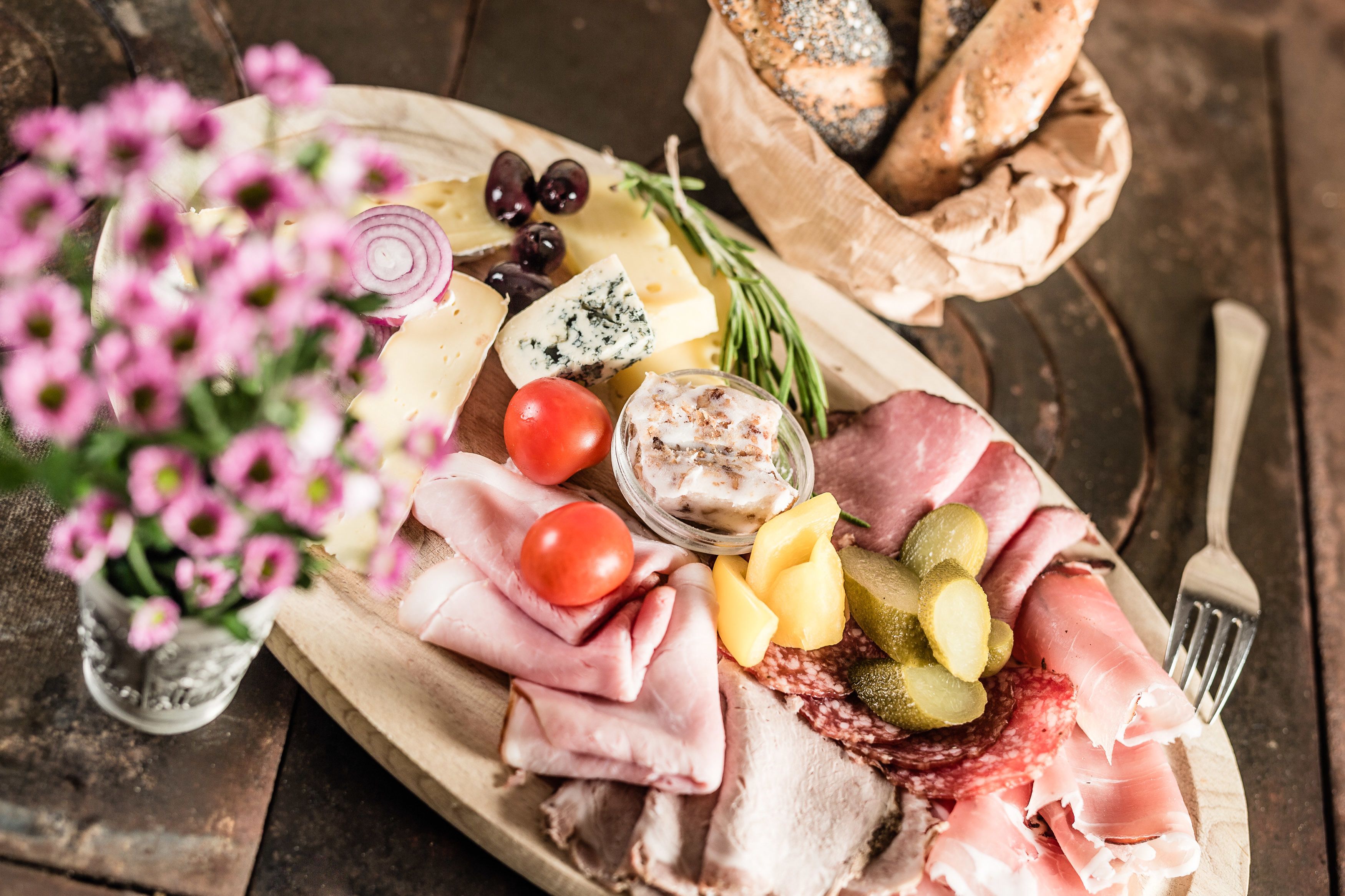 A charcuterie board with various meats, cheeses, olives, and pickles.