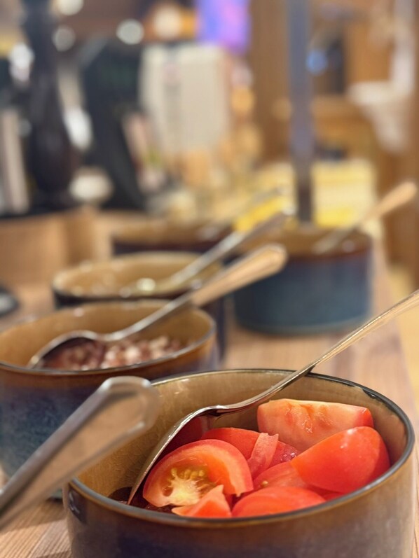 A close-up of a glass mug filled with sliced tomatoes and a spoon. - Hotel Standlhof Zillertal (Uderns)
