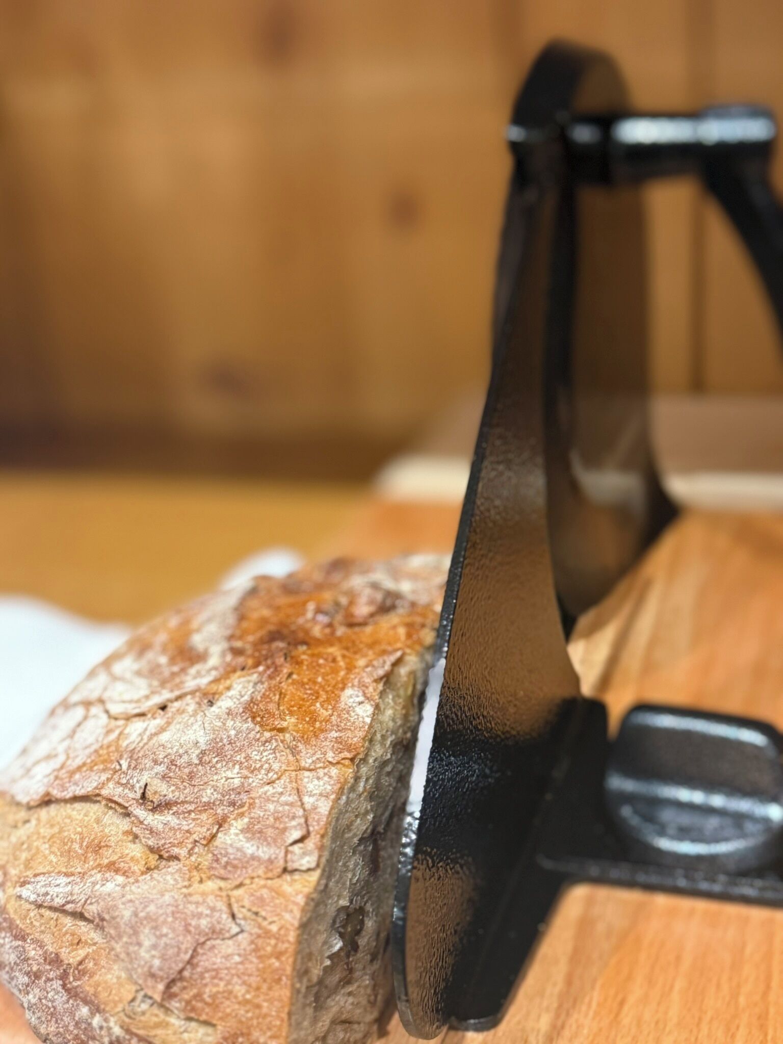 Une miche de pain sur une planche à découper en bois, avec un couteau à pain à manche noir.