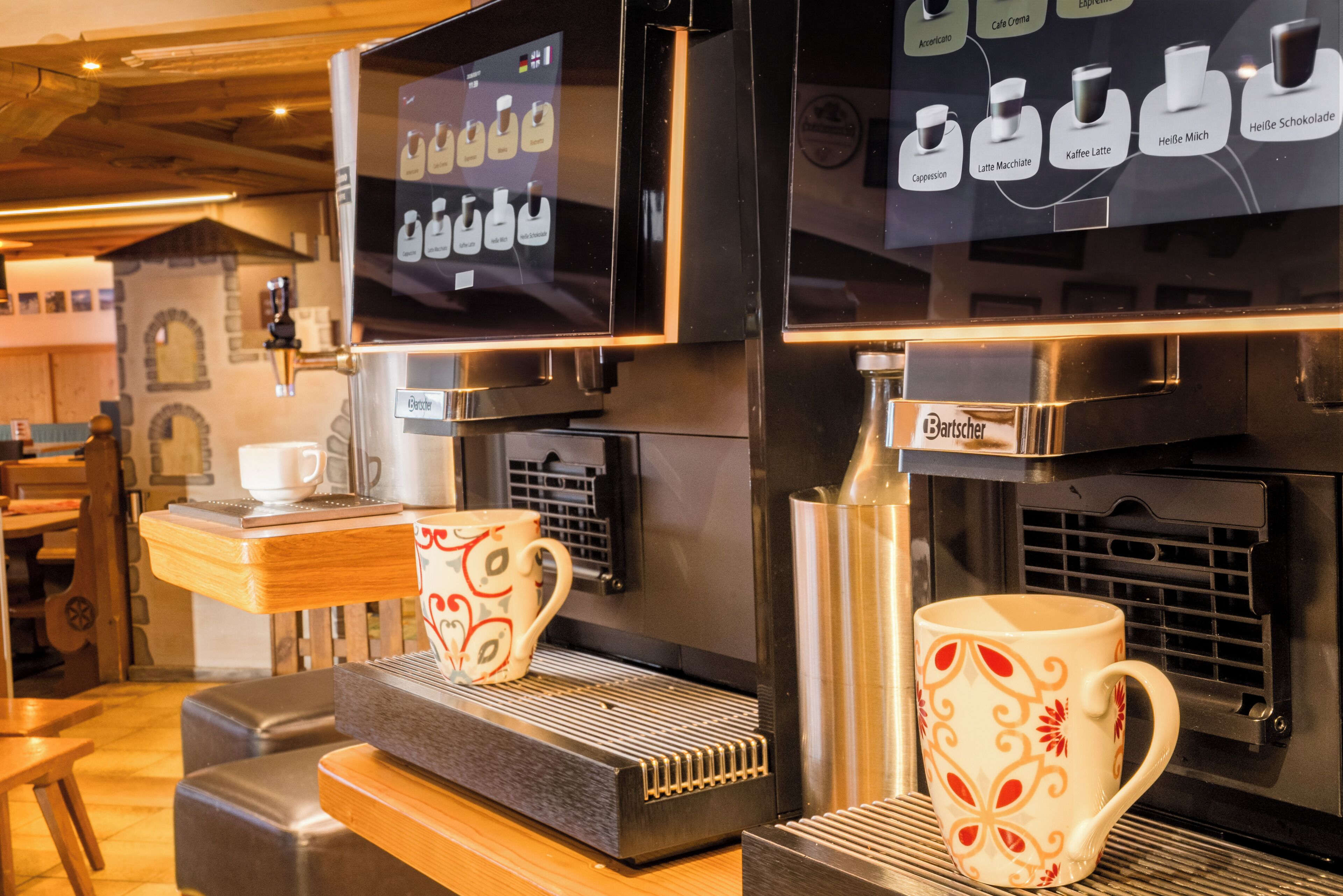 A coffee machine with a digital display, two coffee cups, and a wooden counter.