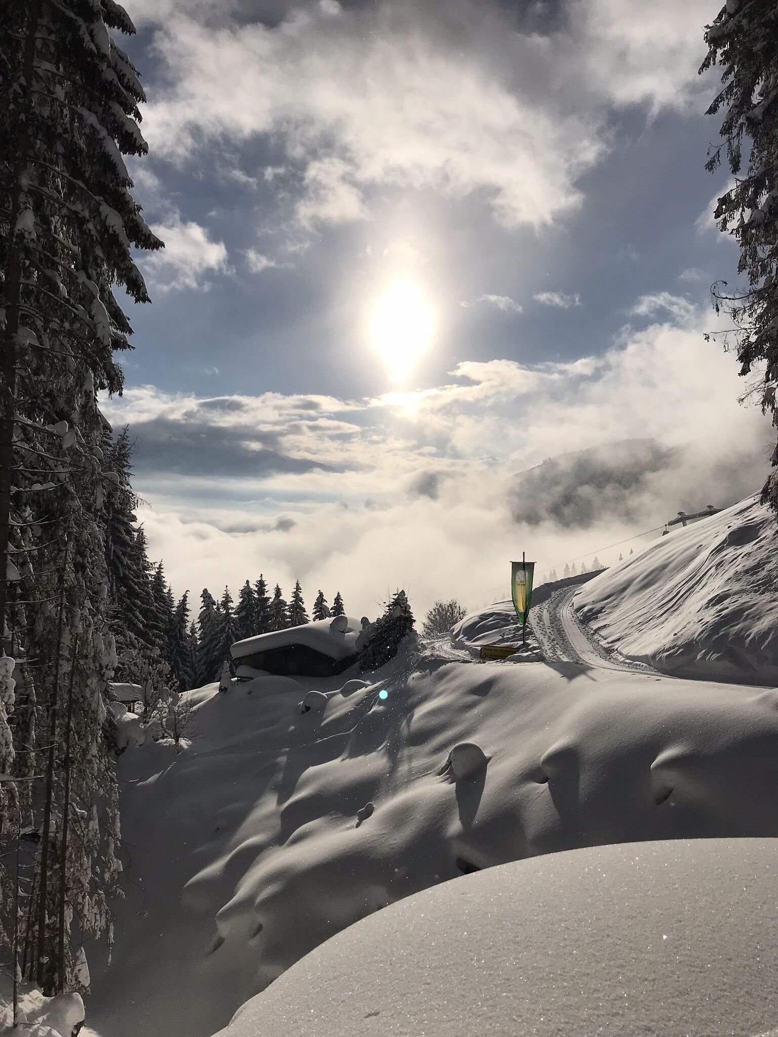 Un paisaje montañoso nevado con cielo despejado y el sol brillando.