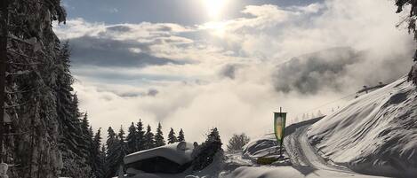 Un paisaje montañoso nevado con cielo despejado y el sol brillando.