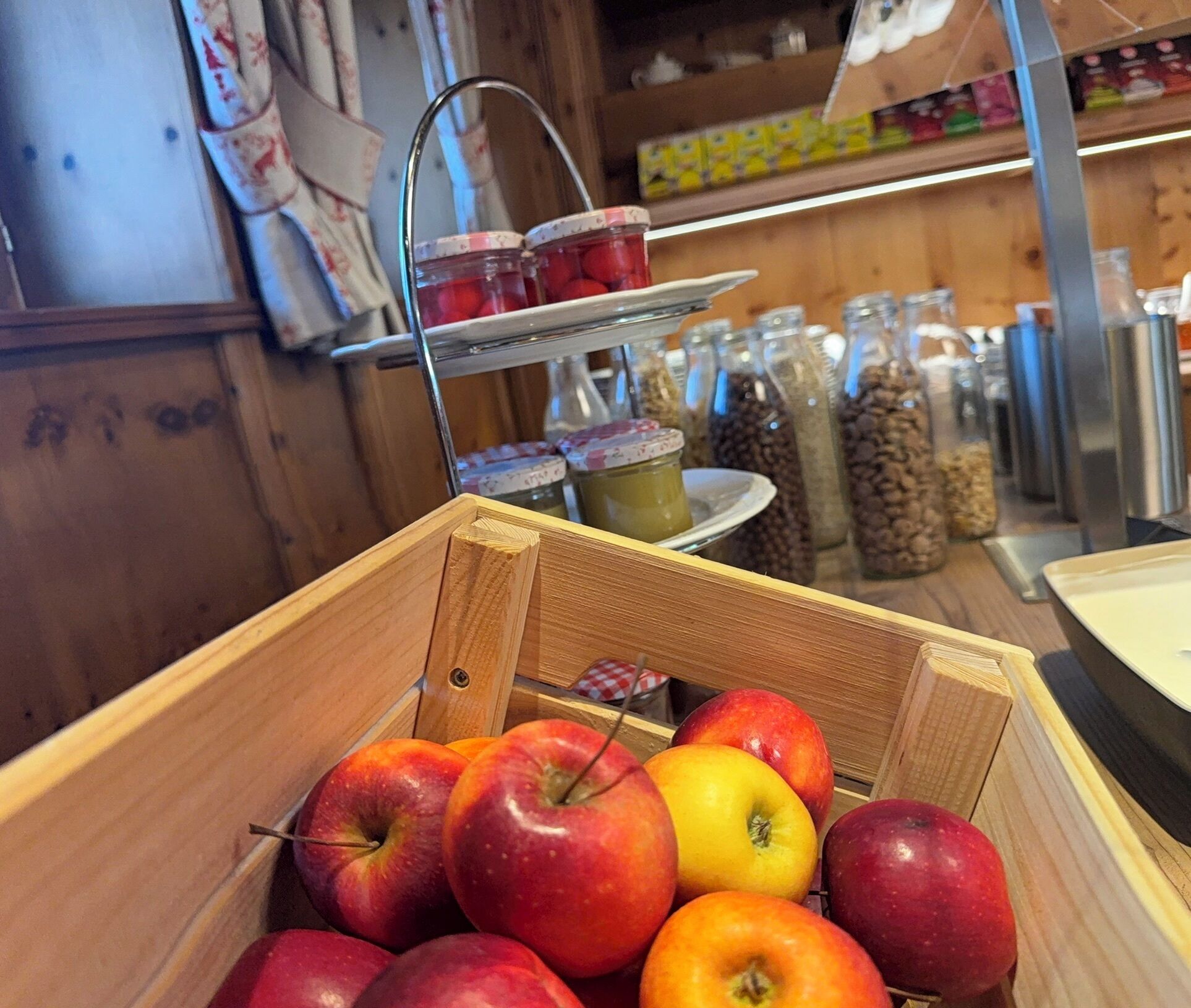 A wooden crate filled with apples and jars of preserves in a rustic setting.