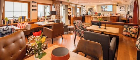 Un hall de hotel con zonas de estar, una recepción y un bar.