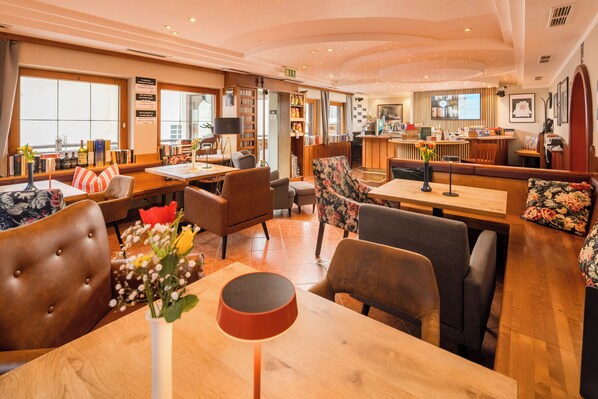 Un hall de hotel con zonas de estar, una recepción y un bar.