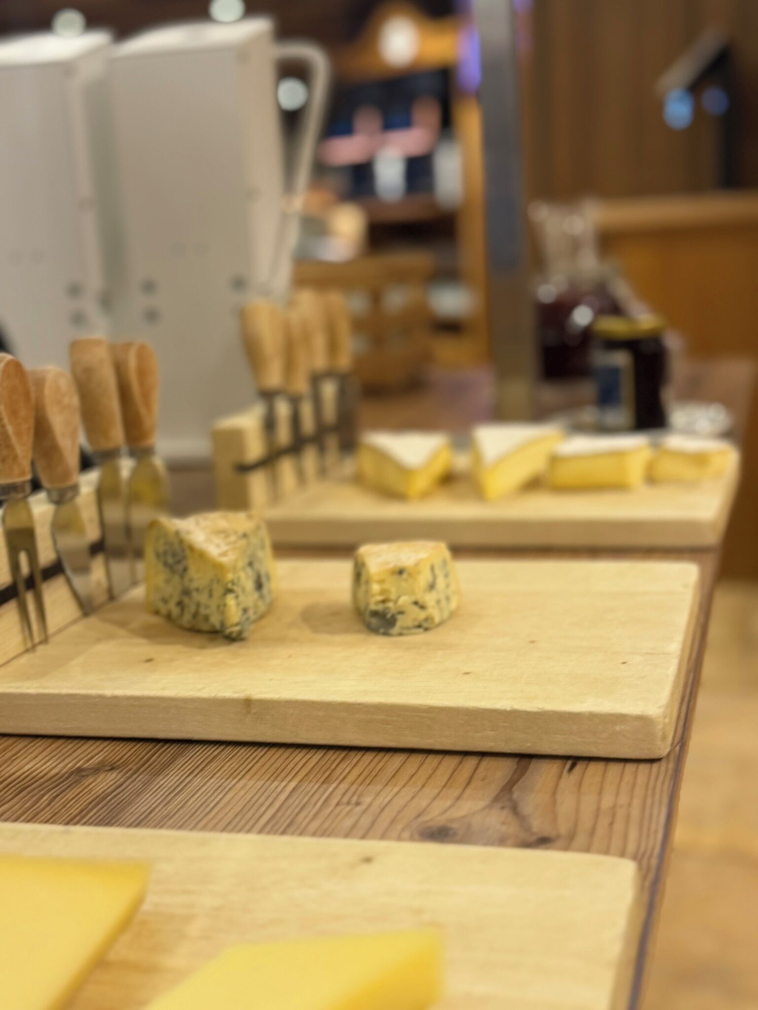 A cheese board with various types of cheese and wooden cheese knives.