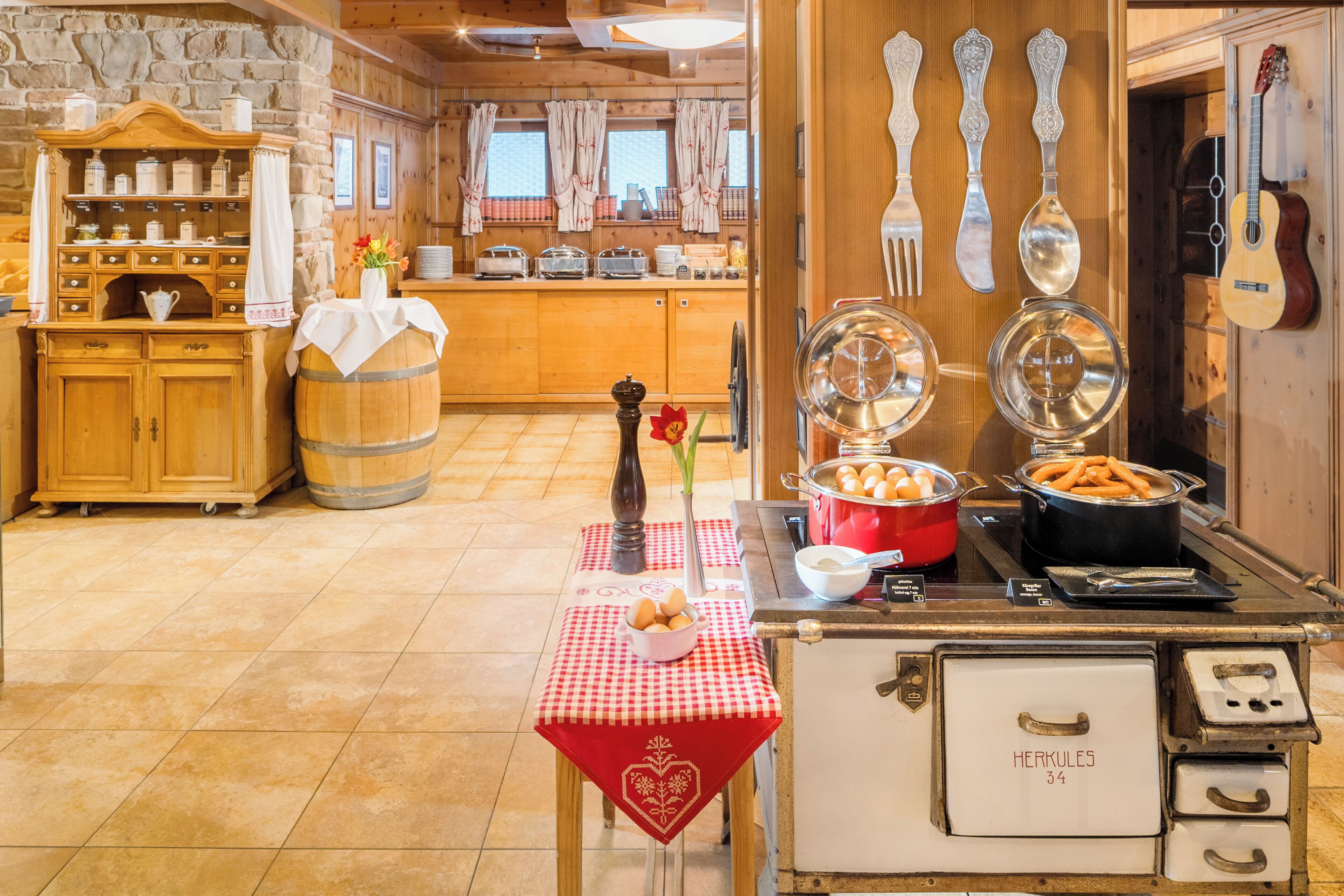 A kitchen with wooden cabinets, a stone wall, and a table with a red tablecloth.