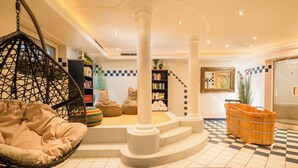 A modern interior with a hanging chair, a staircase with a unique design, a bookshelf, and a large basket. - Hotel Standlhof Zillertal (Uderns)