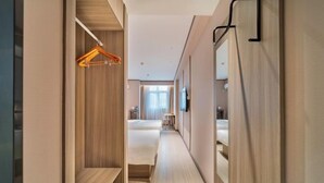 A hotel corridor with wooden walls, a hanging garment rack, and a bed in the distance. - HanTing Hotel (Chongqing Jiazhou Huahuiyuan Subway Station) (Chongqing)