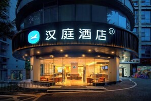A hotel with a curved facade, a prominent sign with a logo, and a well-lit entrance. - HanTing Hotel (Chongqing Jiazhou Huahuiyuan Subway Station) (Chongqing)