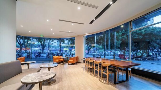 A modern indoor seating area with tables and chairs, large windows with a view of the street, and a ceiling with recessed lighting. - HanTing Hotel (Chongqing Jiazhou Huahuiyuan Subway Station) (Chongqing)