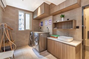 A modern kitchen with wooden cabinetry, a built-in washing machine, a sink, and a window.