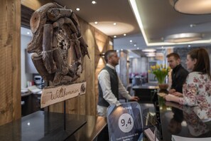 A wooden sculpture with a sign that reads 'Willkommen' in a hotel lobby.