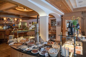 A buffet area with various food items and a bar with glassware.