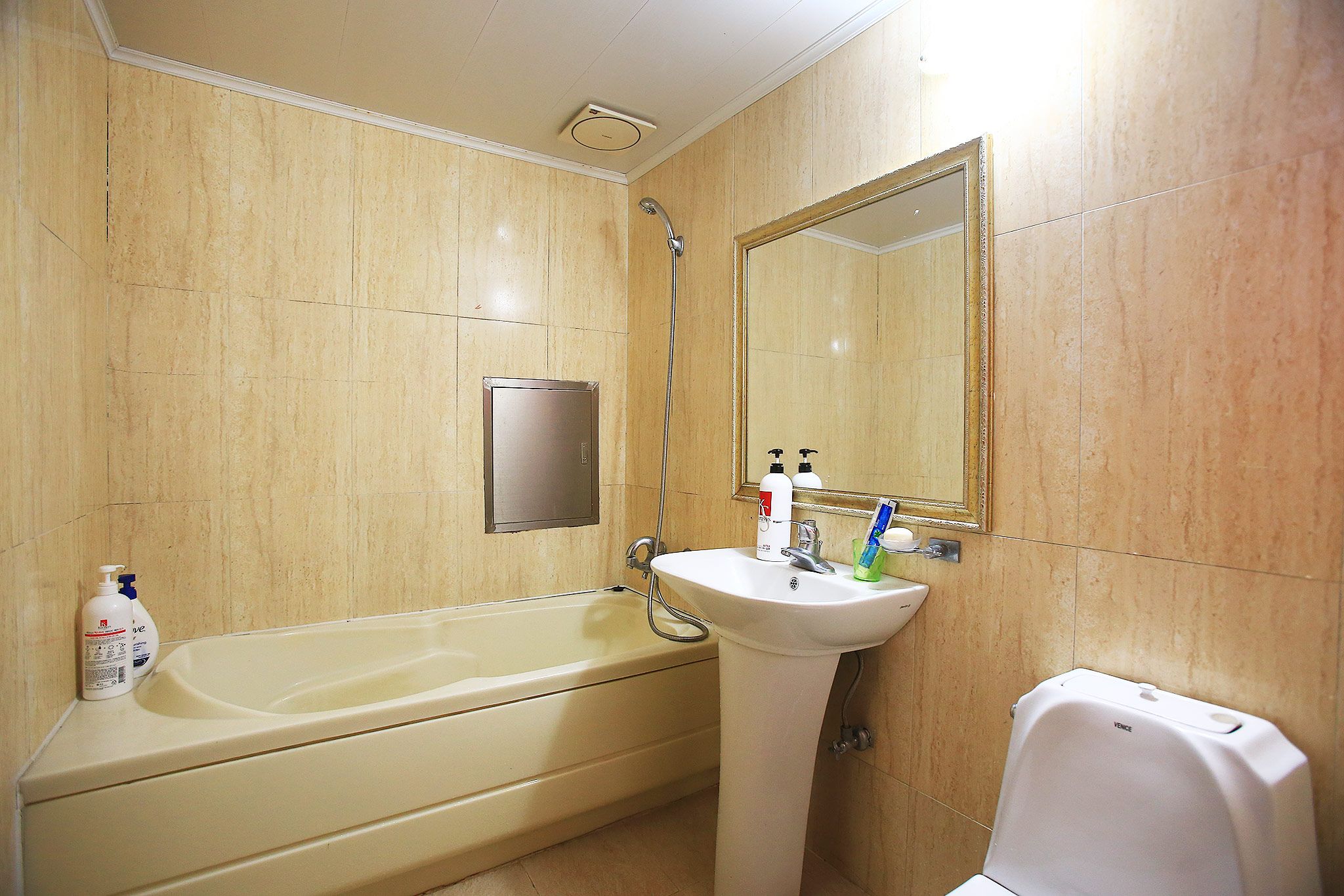 A bathroom with a bathtub, a sink, a mirror, and toiletries.